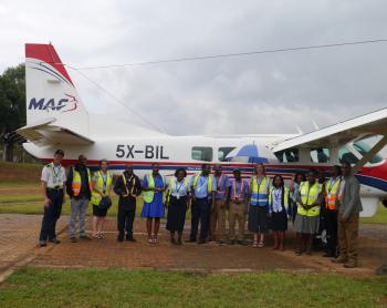 MAF Uganda's staff gathered between the wings of Cessna 208 Caravan for the last time