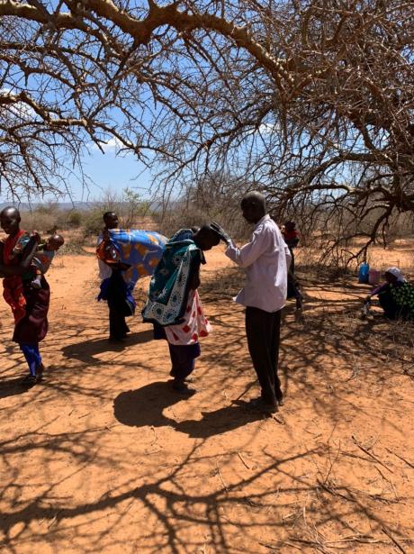 A young mother bows her head for a Maasai village elder to touch.