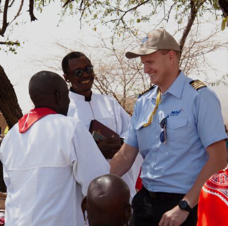 MAF Pilot Peter Griffin shaking hands with the son of a previous traditional healer, as  MDTC founder evangelist Elisha Moita joins in the joy of seeing lives changed by the love of Christ