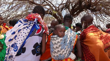 Women and children gathered under the tree waiting for medical care